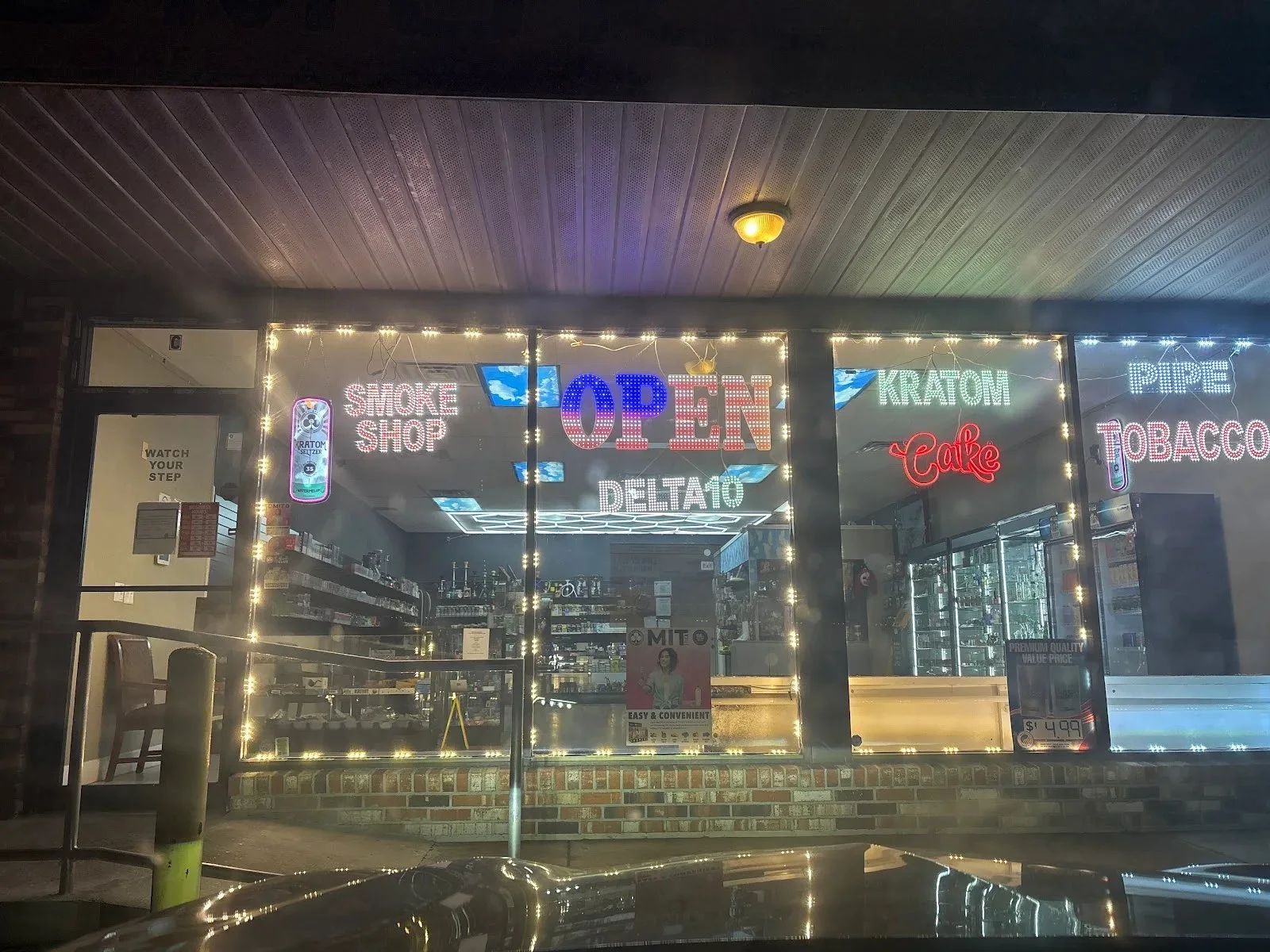 White Cloud 2 Smoke Shop lit at night, the window neon reading Smoke Shop, Open, Delta 10, Kratom and Tobacco